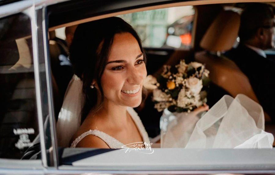 Novia en coche con ramos de novia el día de su boda